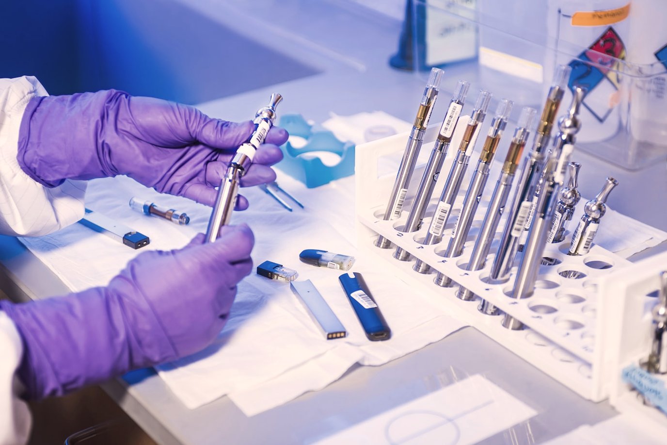 Gloved hands loading a sample into a rack of labelled tubes during analytical sample preparation.
