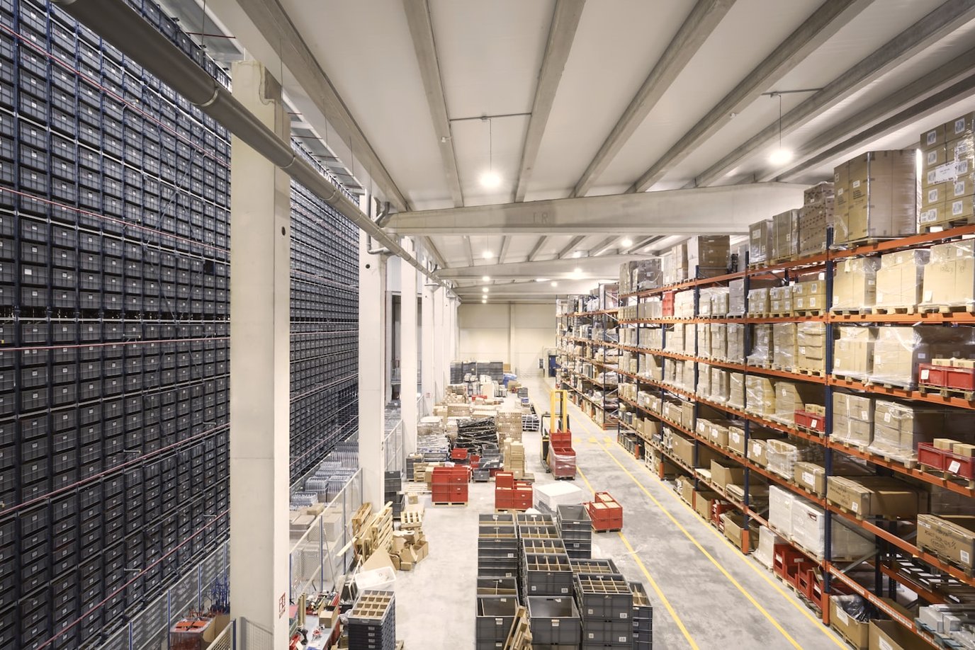 Long warehouse aisle lined floor to ceiling with racked cartons and pallets.
